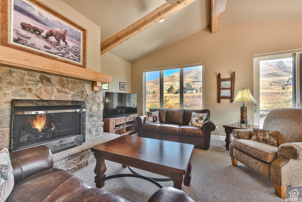 Carpeted living room featuring plenty of natural light, high vaulted ceiling, beam ceiling, and a stone fireplace