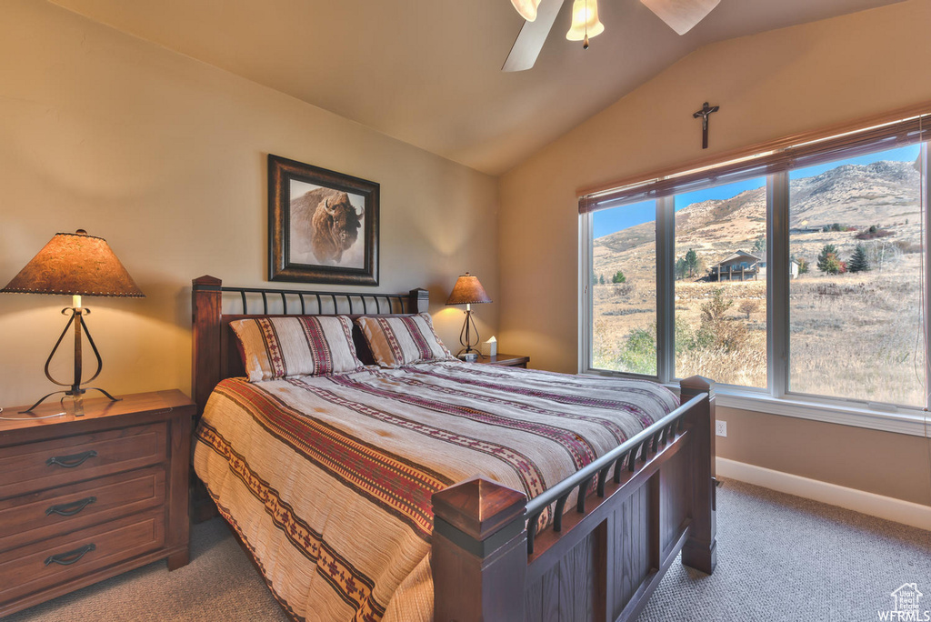 Carpeted bedroom featuring a mountain view, vaulted ceiling, and ceiling fan