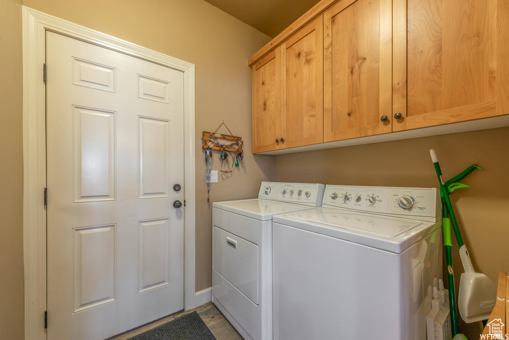 Laundry room featuring light tile floors, washer and dryer, and cabinets