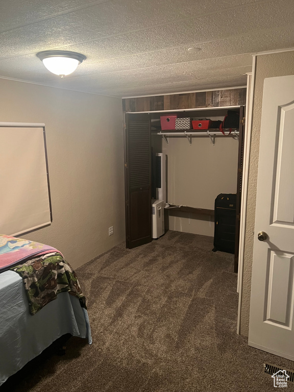 Unfurnished bedroom with dark colored carpet and a textured ceiling