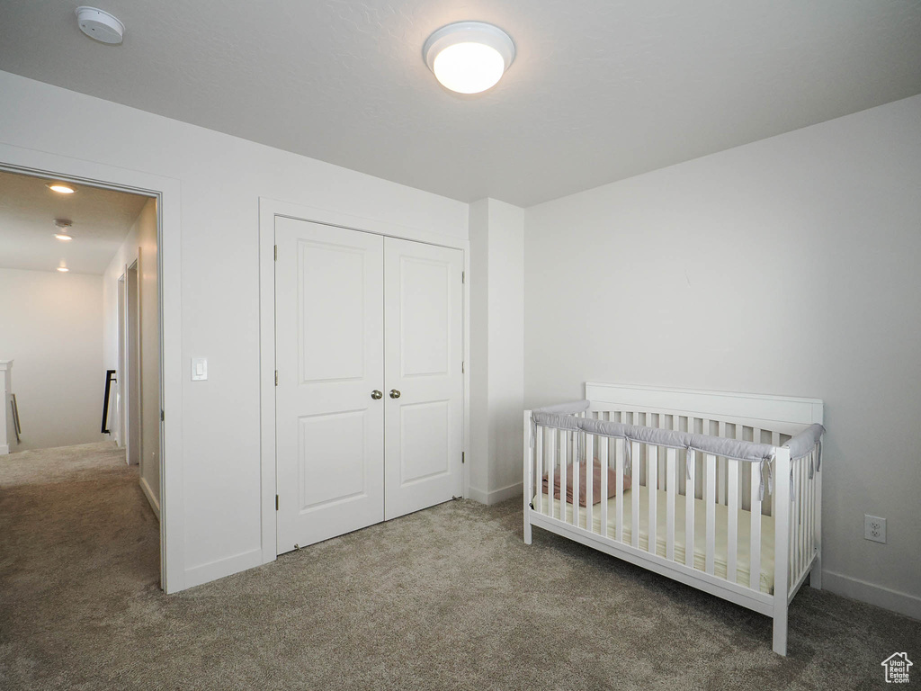 Bedroom featuring a closet, dark colored carpet, and a nursery area