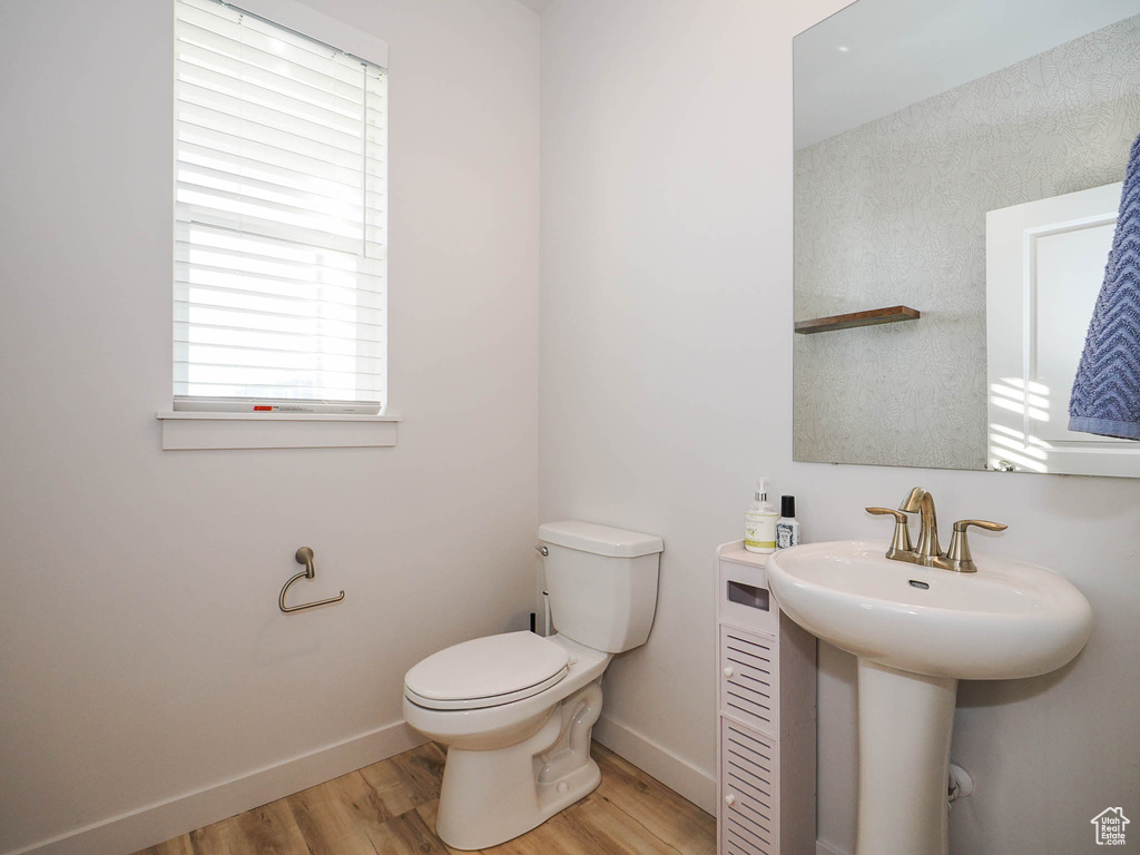 Bathroom with hardwood / wood-style floors, a healthy amount of sunlight, and toilet