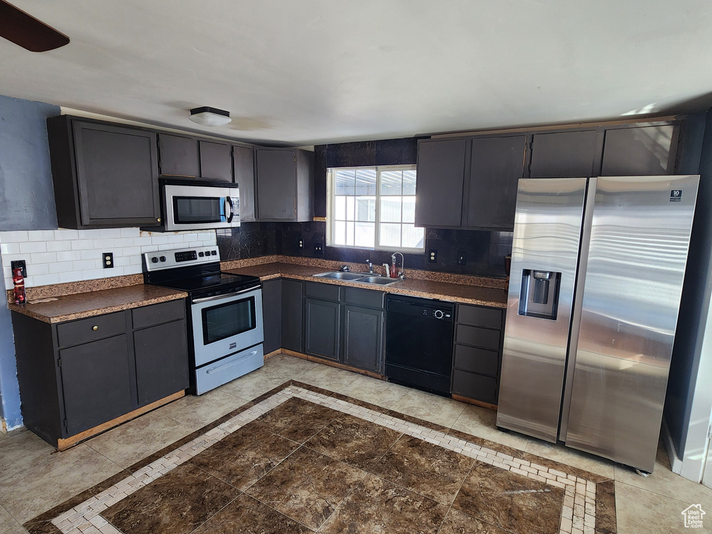 Kitchen with ceiling fan, tasteful backsplash, sink, stainless steel appliances, and light tile flooring