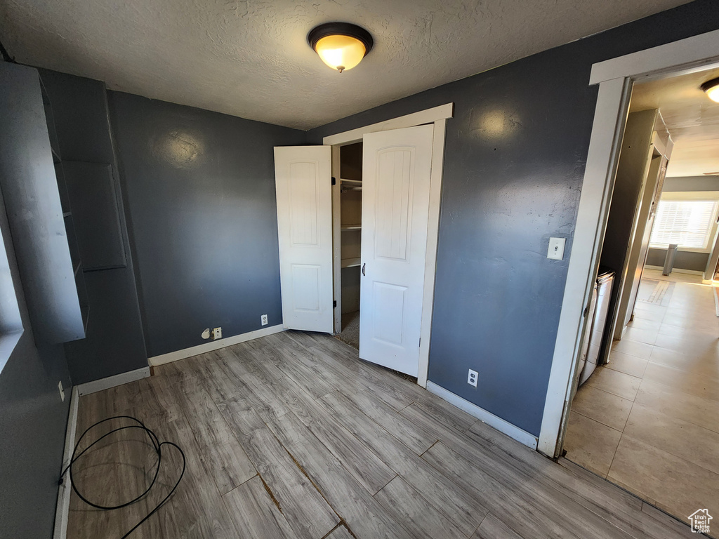 Unfurnished bedroom with a closet, light hardwood / wood-style flooring, and a textured ceiling
