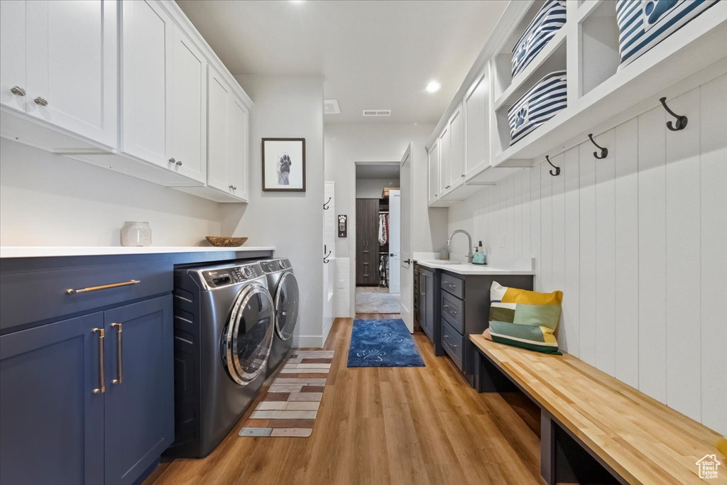 Laundry room with cabinets, light hardwood / wood-style floors, sink, and independent washer and dryer