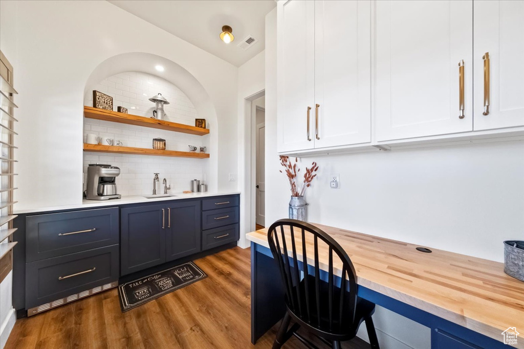 Kitchen featuring dark hardwood / wood-style flooring, white cabinetry, backsplash, sink, and vaulted ceiling