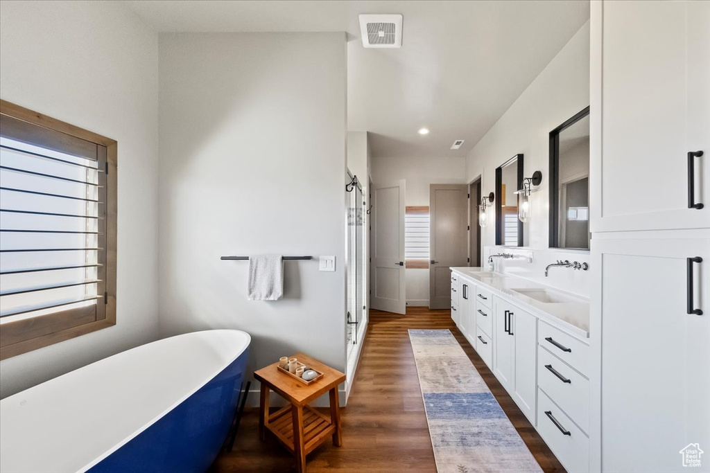Bathroom featuring a tub, hardwood / wood-style flooring, and dual vanity