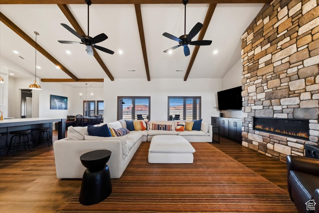 Living room featuring dark wood-type flooring, beam ceiling, and ceiling fan