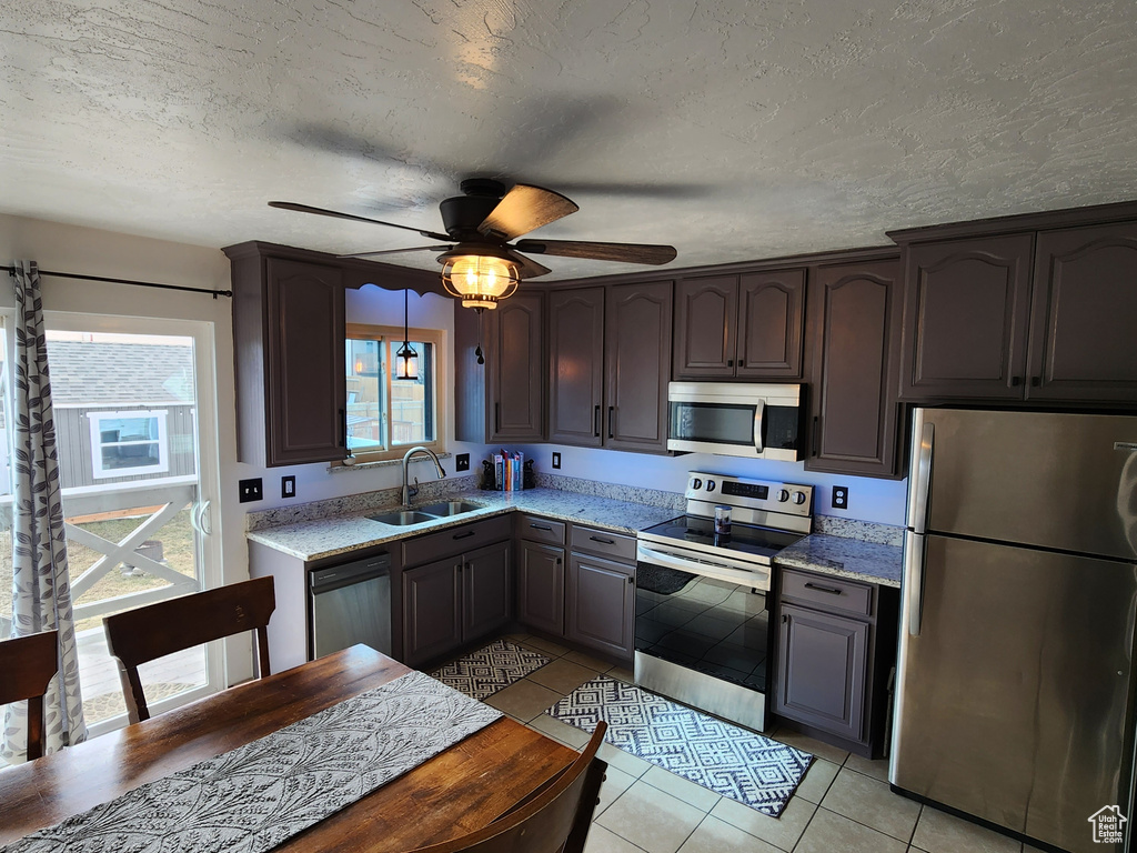 Kitchen featuring a textured ceiling, ceiling fan, sink, light tile floors, and appliances with stainless steel finishes