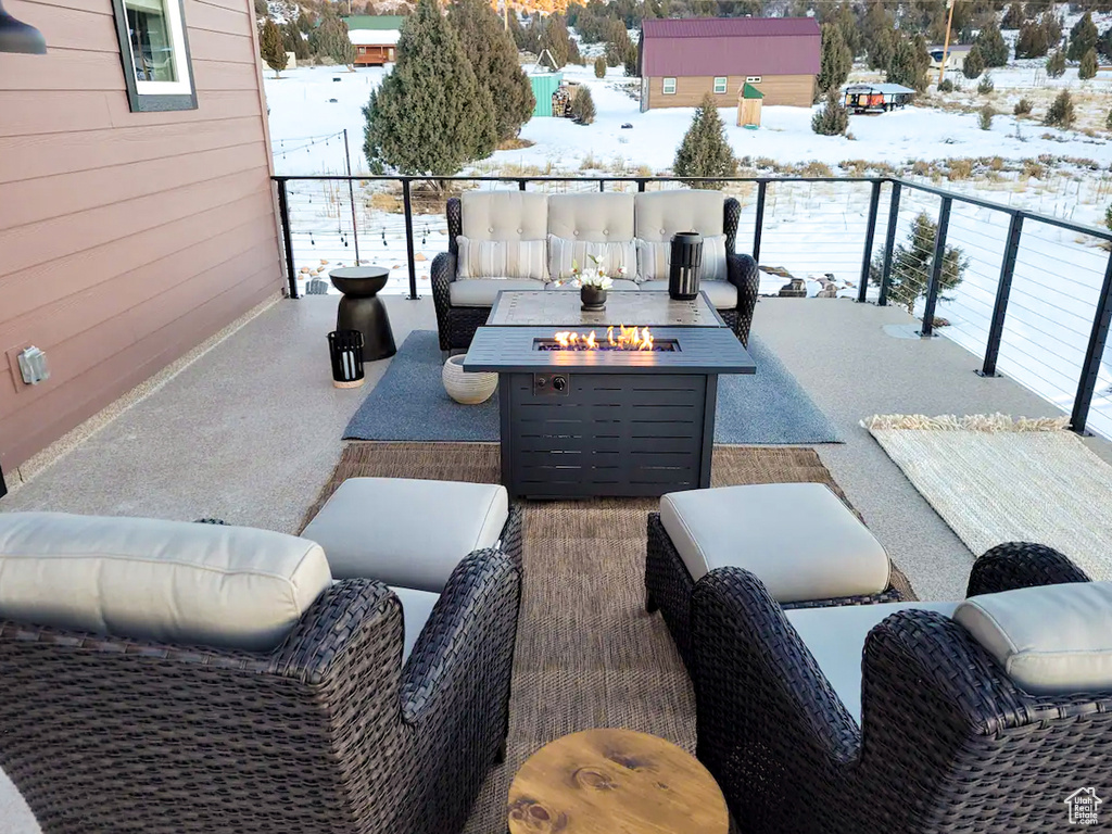 Snow covered patio with a balcony and an outdoor living space with a fire pit