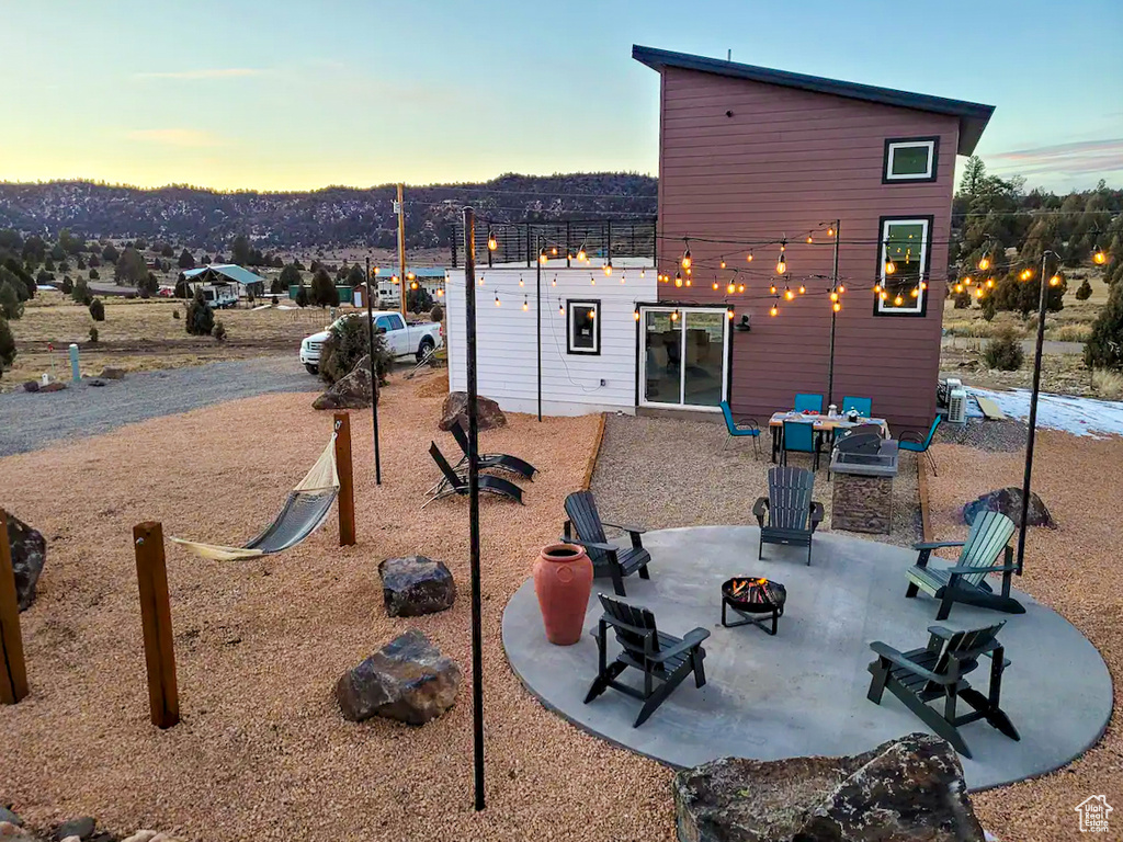 Back house at dusk featuring a patio and a fire pit