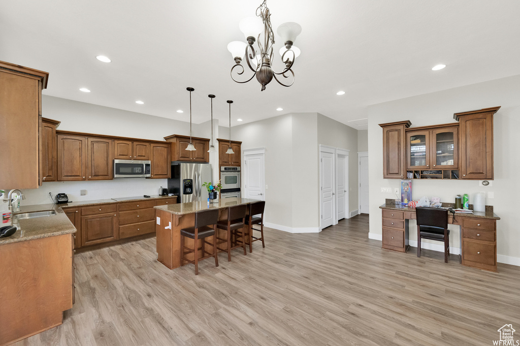 Kitchen featuring pendant lighting, a kitchen island, a chandelier, appliances with stainless steel finishes, and a kitchen breakfast bar