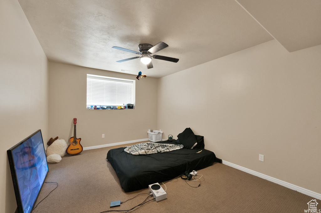 Workout room featuring ceiling fan and dark carpet