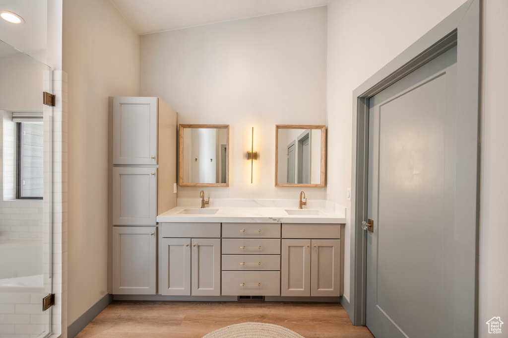 Bathroom with lofted ceiling, dual bowl vanity, and wood-type flooring