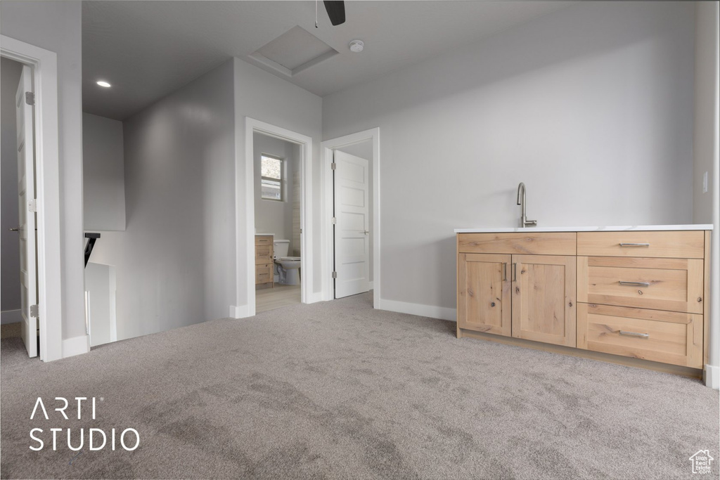 Interior space featuring connected bathroom, sink, ceiling fan, and light colored carpet