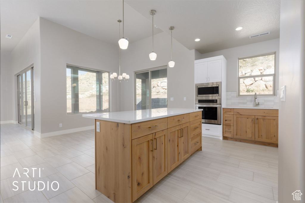 Kitchen featuring hanging light fixtures, light tile floors, stainless steel appliances, and backsplash