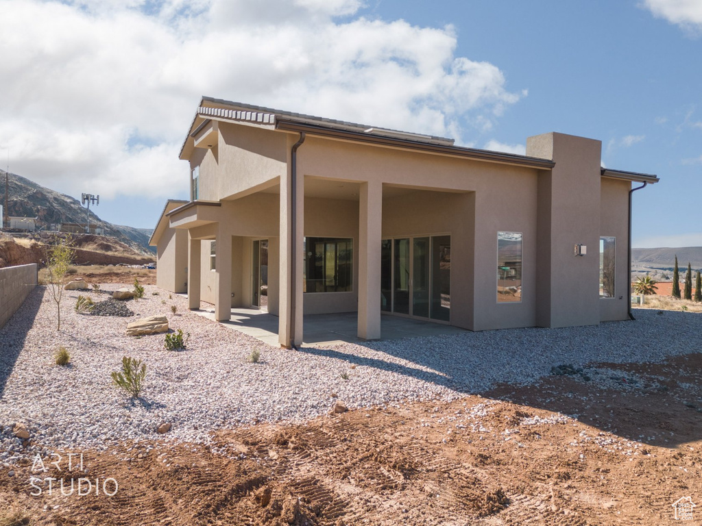 Rear view of house featuring a mountain view and a patio area