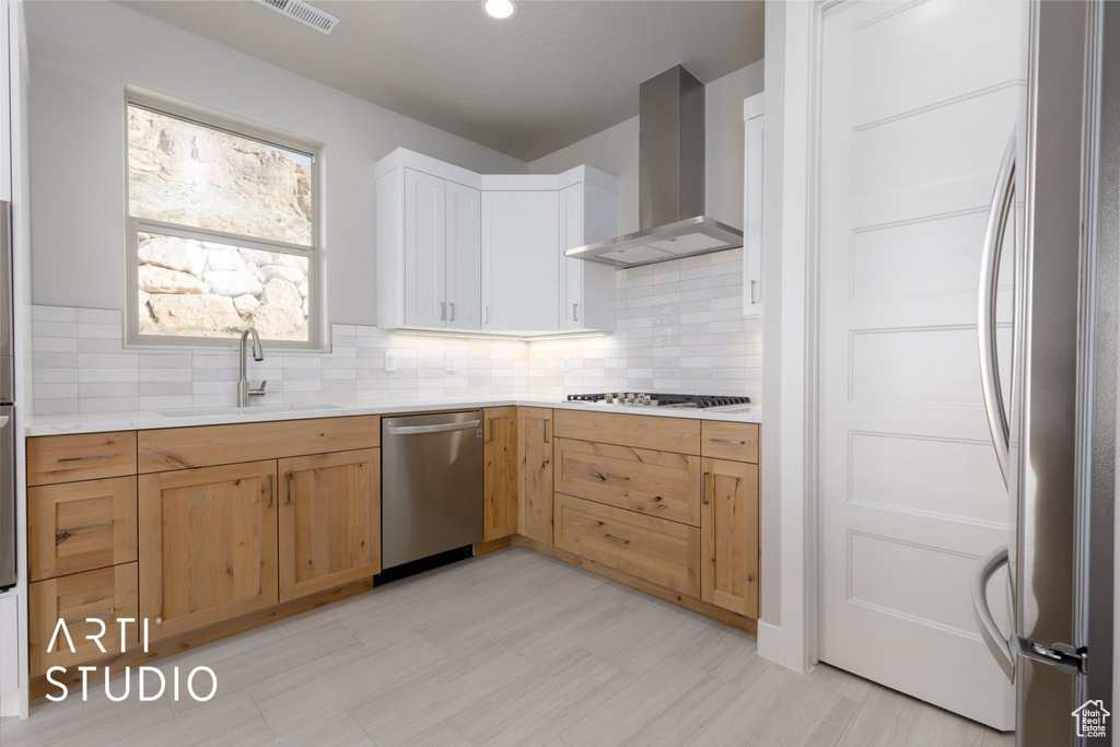 Kitchen with backsplash, sink, light tile floors, appliances with stainless steel finishes, and wall chimney exhaust hood