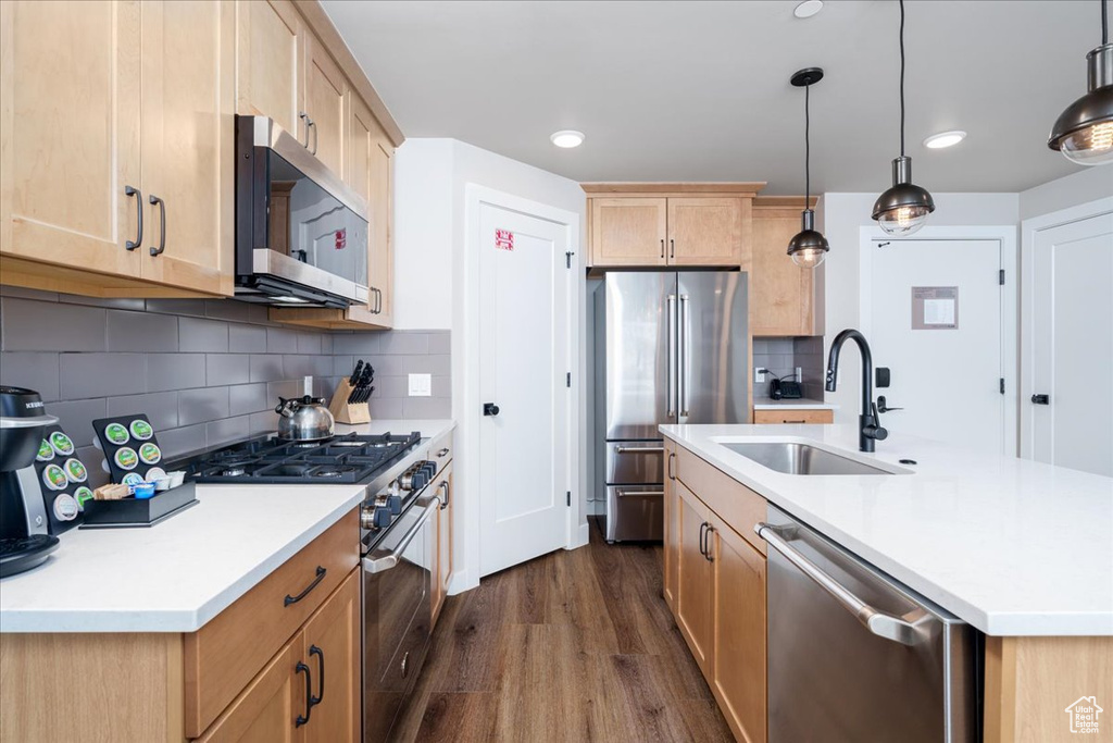 Kitchen with tasteful backsplash, dark hardwood / wood-style flooring, high end appliances, and a kitchen island with sink