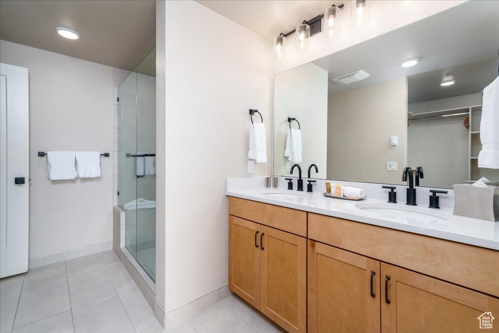 Bathroom featuring dual sinks, walk in shower, large vanity, and tile flooring