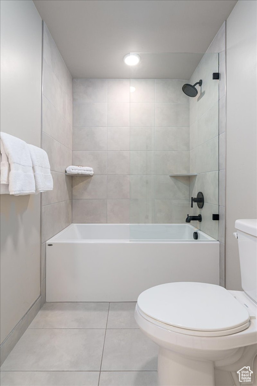 Bathroom featuring toilet, tiled shower / bath combo, and tile floors