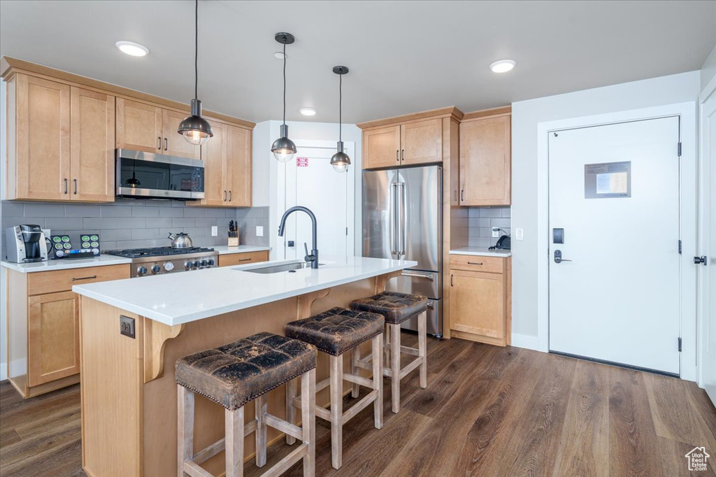 Kitchen featuring backsplash, hanging light fixtures, dark hardwood / wood-style flooring, sink, and appliances with stainless steel finishes