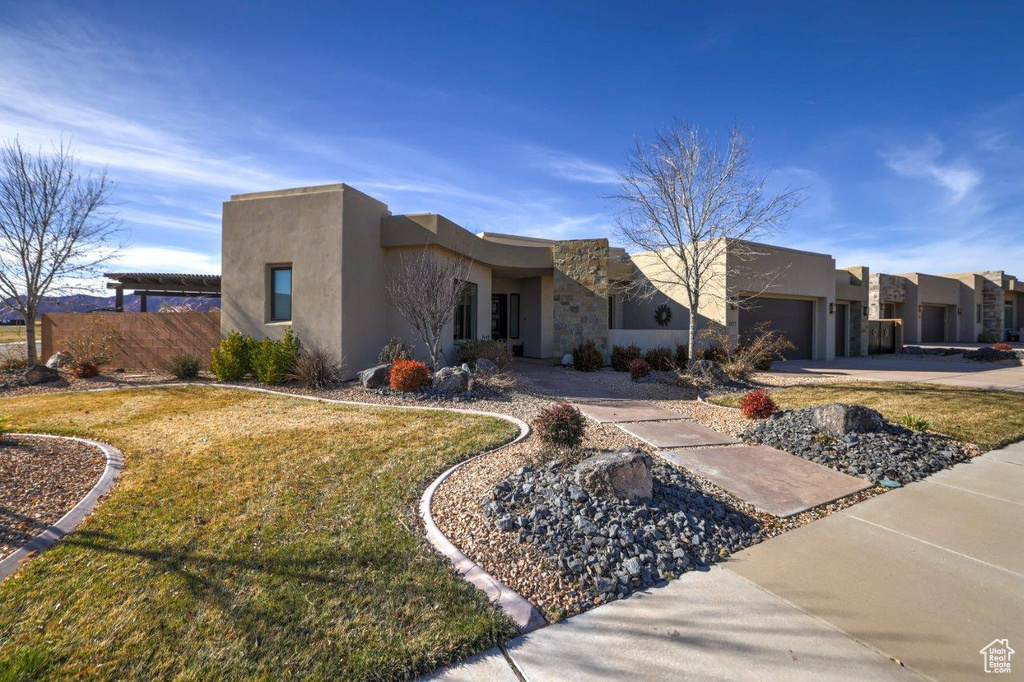 Pueblo revival-style home featuring a front lawn