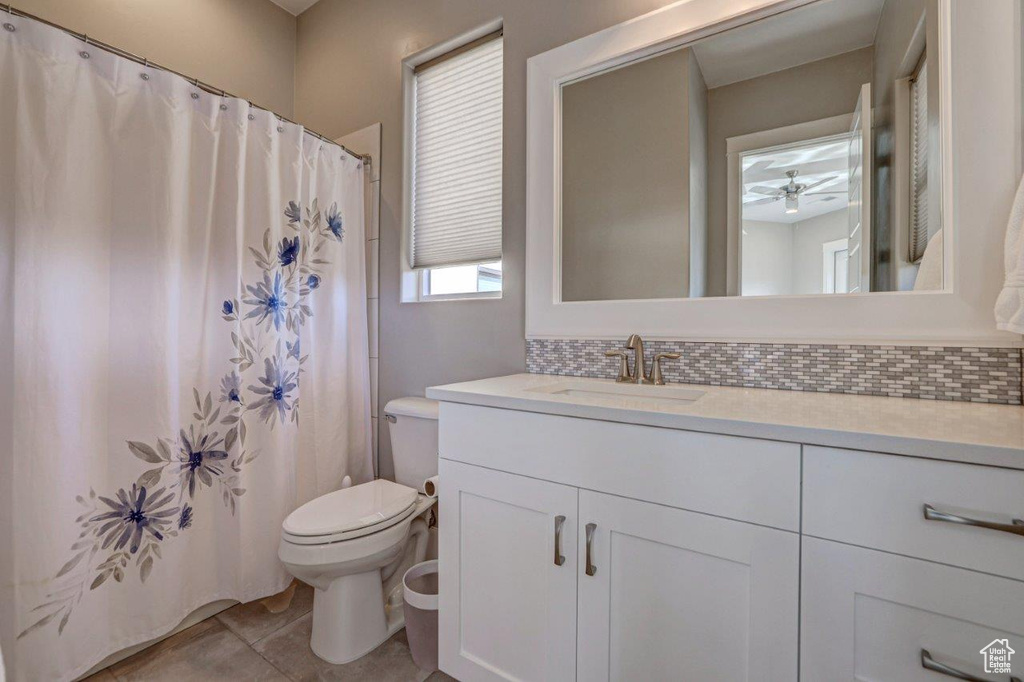 Bathroom with backsplash, ceiling fan, toilet, large vanity, and tile flooring
