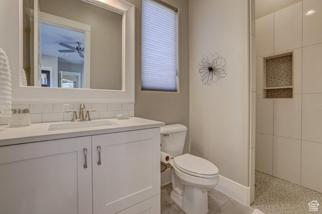 Bathroom with large vanity, toilet, tasteful backsplash, tile flooring, and ceiling fan