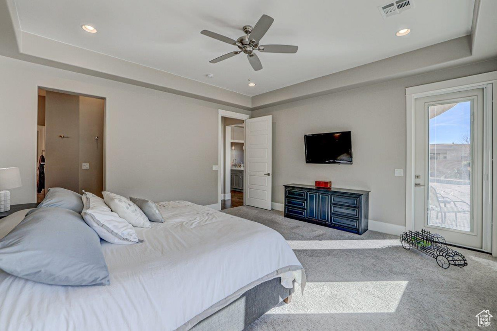 Carpeted bedroom featuring a raised ceiling, ceiling fan, and access to outside