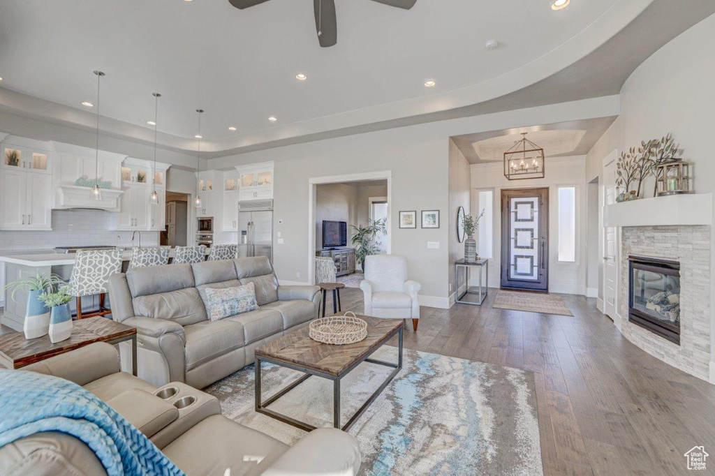 Living room featuring light hardwood / wood-style flooring, a tray ceiling, and ceiling fan with notable chandelier