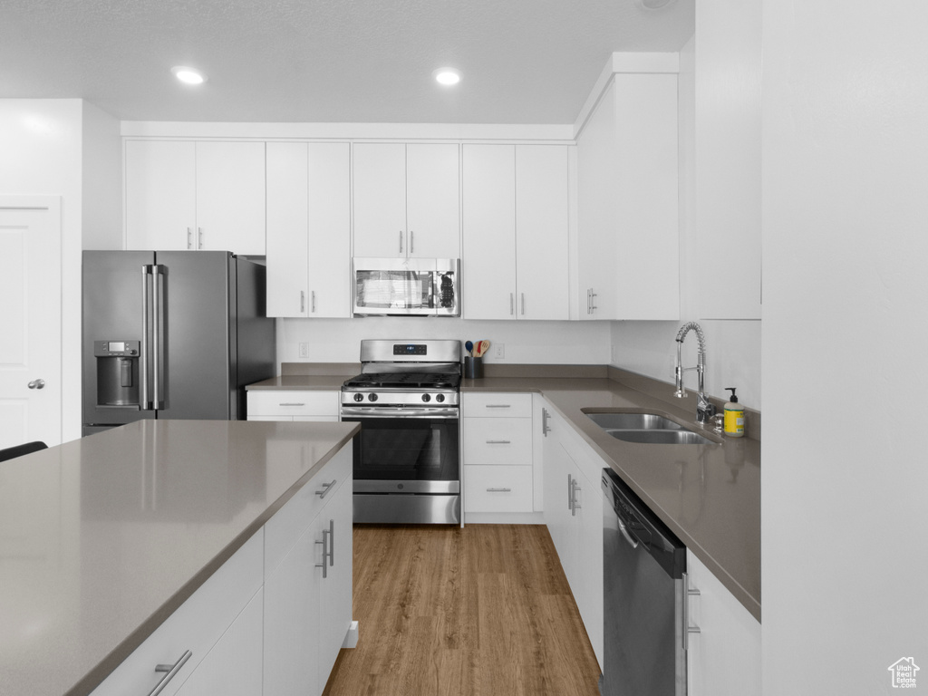 Kitchen featuring white cabinets, light hardwood / wood-style floors, stainless steel appliances, and sink
