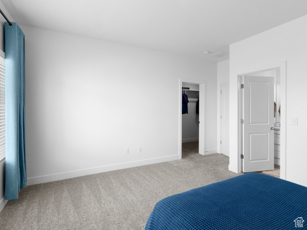 Bedroom with a closet, light carpet, and a walk in closet