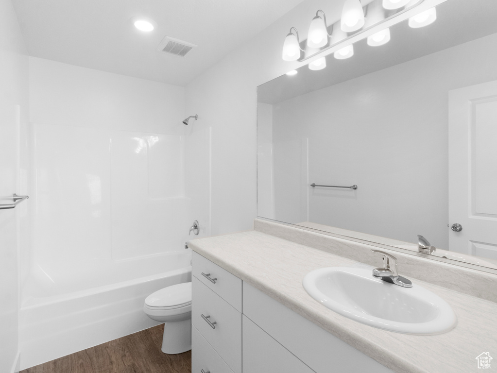 Full bathroom with hardwood / wood-style floors, shower / bathtub combination, oversized vanity, and toilet