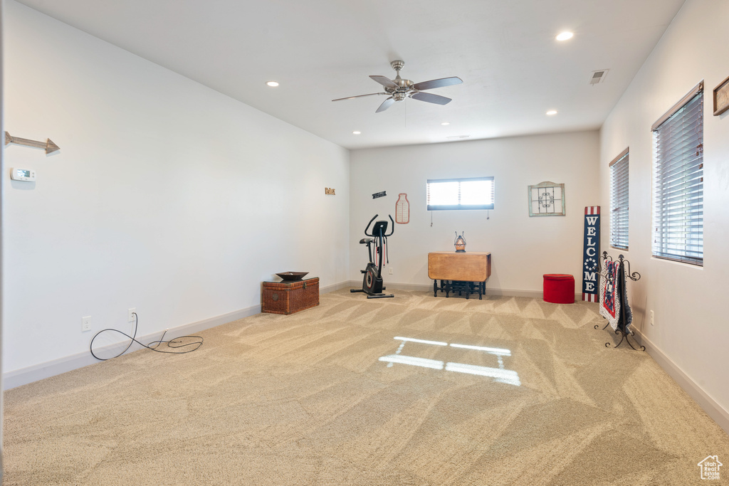 Workout area with ceiling fan and light colored carpet