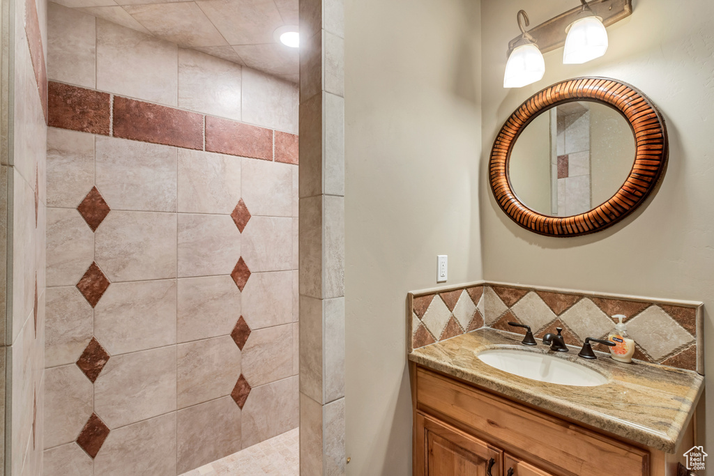 Bathroom featuring a tile shower and vanity with extensive cabinet space