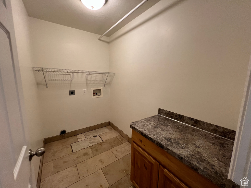 Washroom with light tile flooring, hookup for a washing machine, and electric dryer hookup