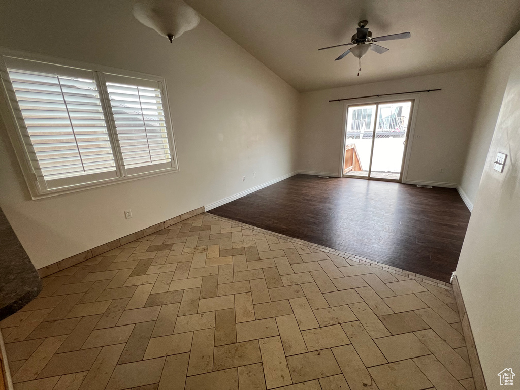 Empty room with dark hardwood / wood-style flooring, ceiling fan, and vaulted ceiling