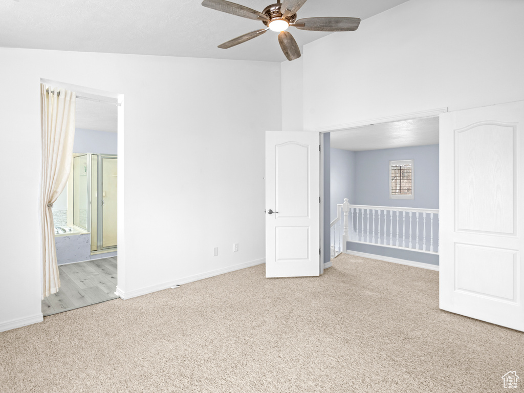 Unfurnished room featuring a wealth of natural light, ceiling fan, light colored carpet, and vaulted ceiling