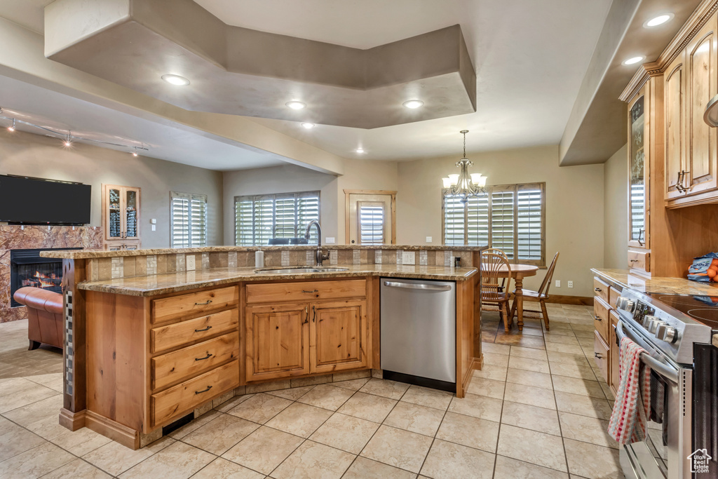 Kitchen featuring light stone countertops, sink, stainless steel appliances, decorative light fixtures, and a chandelier