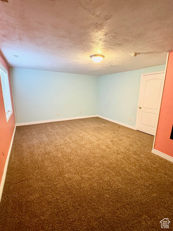 Spare room featuring dark colored carpet and a textured ceiling