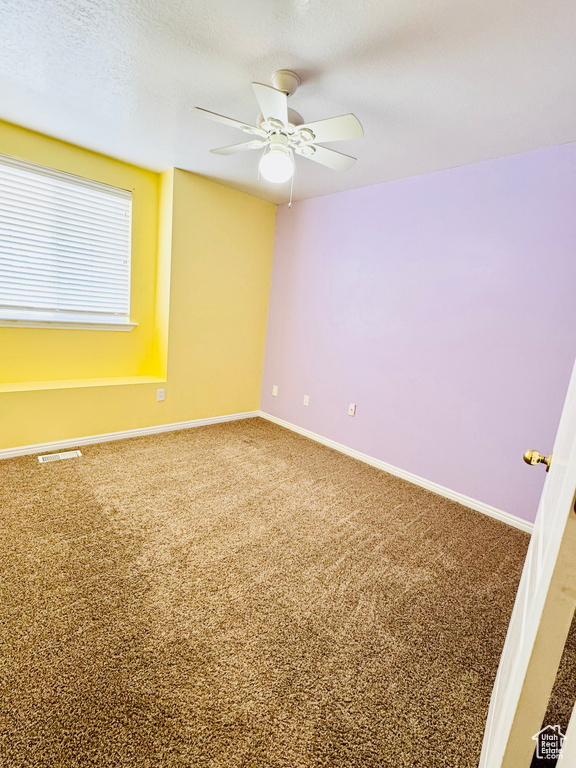 Unfurnished room with ceiling fan, a textured ceiling, and carpet