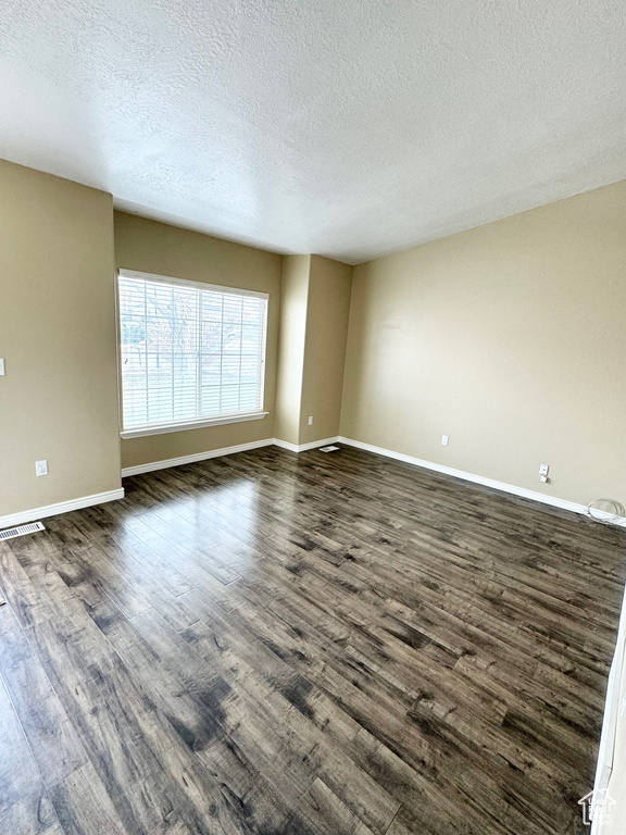 Unfurnished room with dark hardwood / wood-style flooring and a textured ceiling