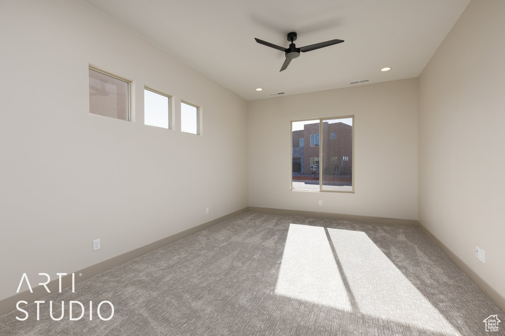 Empty room featuring ceiling fan and dark carpet