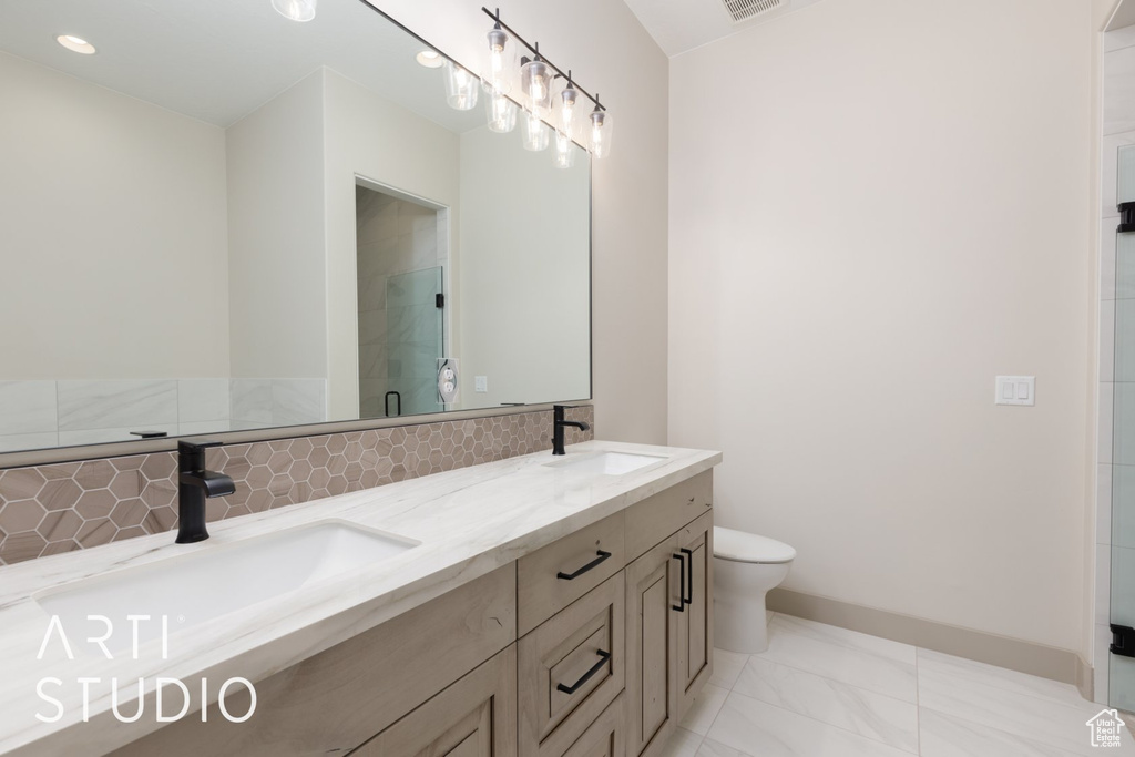 Bathroom featuring toilet, dual sinks, tile floors, and vanity with extensive cabinet space