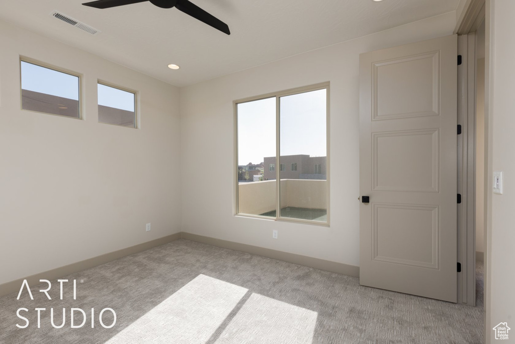 Spare room with a wealth of natural light, ceiling fan, and light carpet