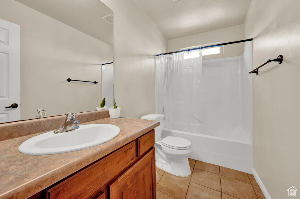 Full bathroom with vanity, toilet, tile floors, and shower / tub combo