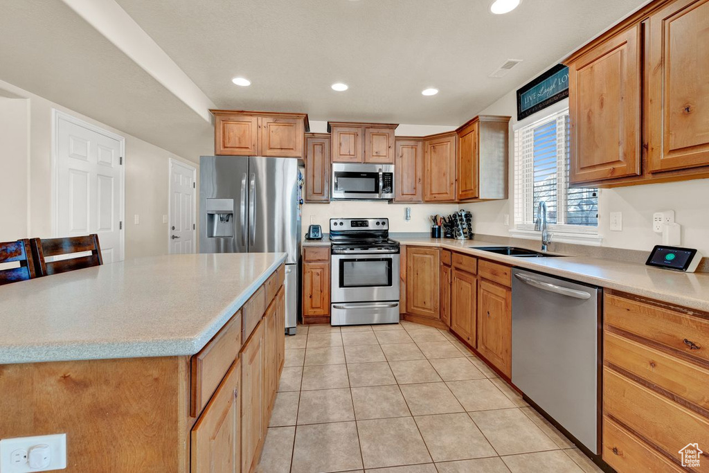 Kitchen featuring sink, light tile floors, stainless steel appliances, and light stone counters