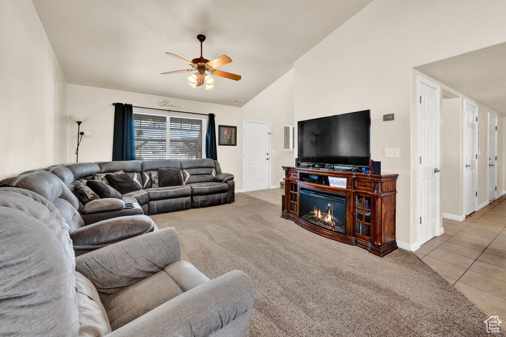 Carpeted living room with ceiling fan and lofted ceiling