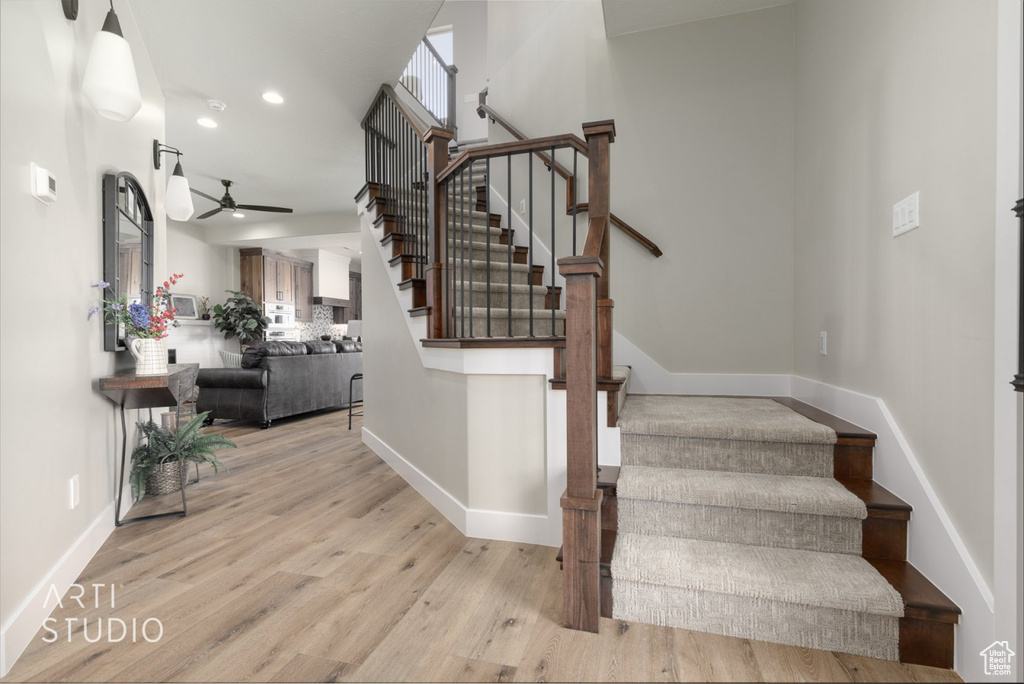 Stairway featuring light hardwood / wood-style floors, ceiling fan, and a towering ceiling